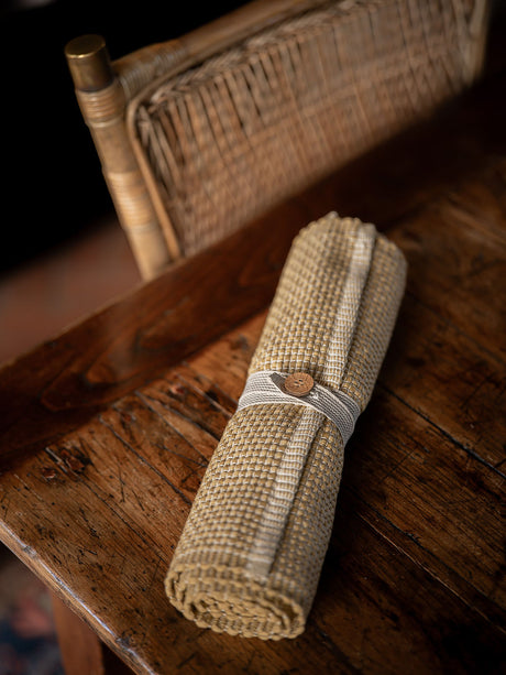 Rolled fabric placemat with a wooden buckle on a rustic wooden surface