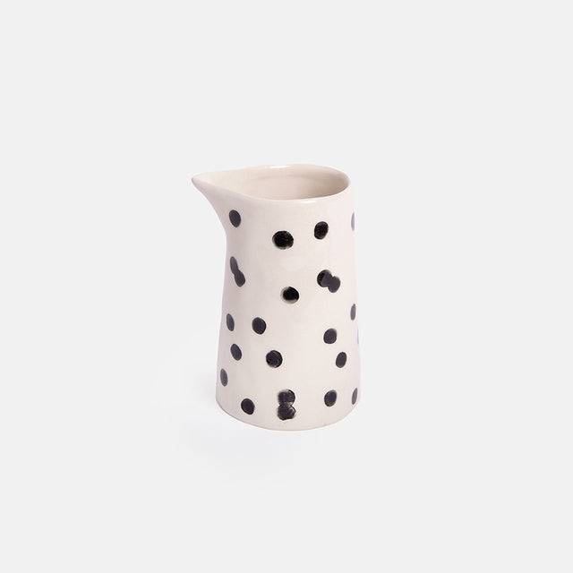 White ceramic pitcher with black polka dots on a white background