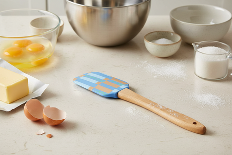 Spatula with a wooden handle and colorful striped head on a white background