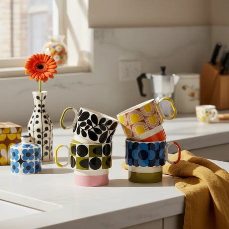 Four colorful mugs with patterned designs on a light beige background