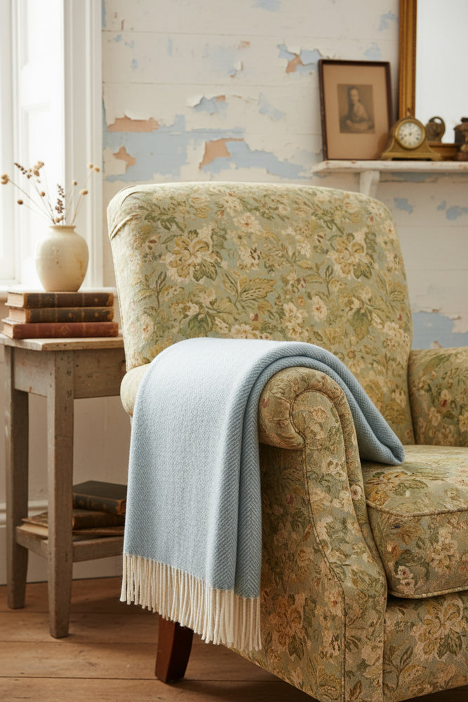 A duck egg blue wool throw with a classic herringbone pattern and tassels at the bottom.