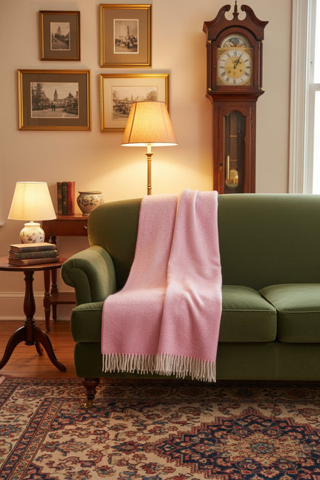 Pink woven blanket with white fringe on a white background
