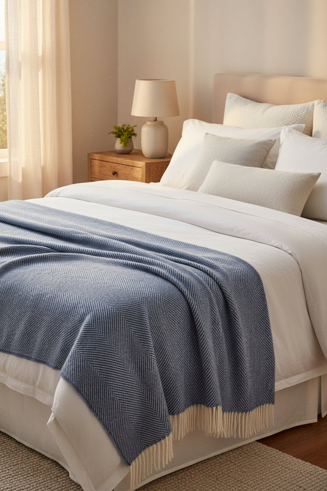 Blue woven blanket with white fringe on a white background