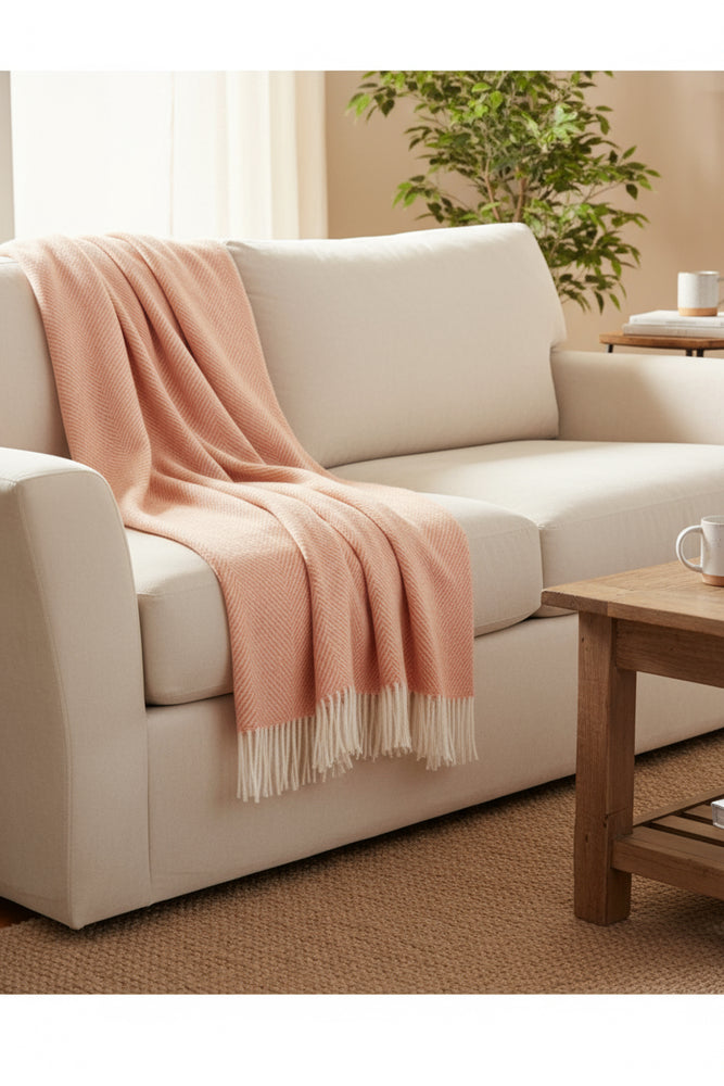 Light orange woven blanket with white fringe on a white background