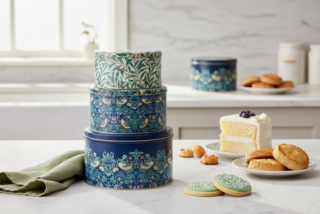 Stack of three decorative tin boxes with floral and bird patterns on a white background