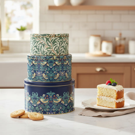 Stack of three decorative tin boxes with floral and bird patterns on a white background
