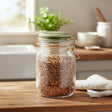 A clear glass jar with a green metal lid and gold-tone wire bail closure, shown on a plain white background.