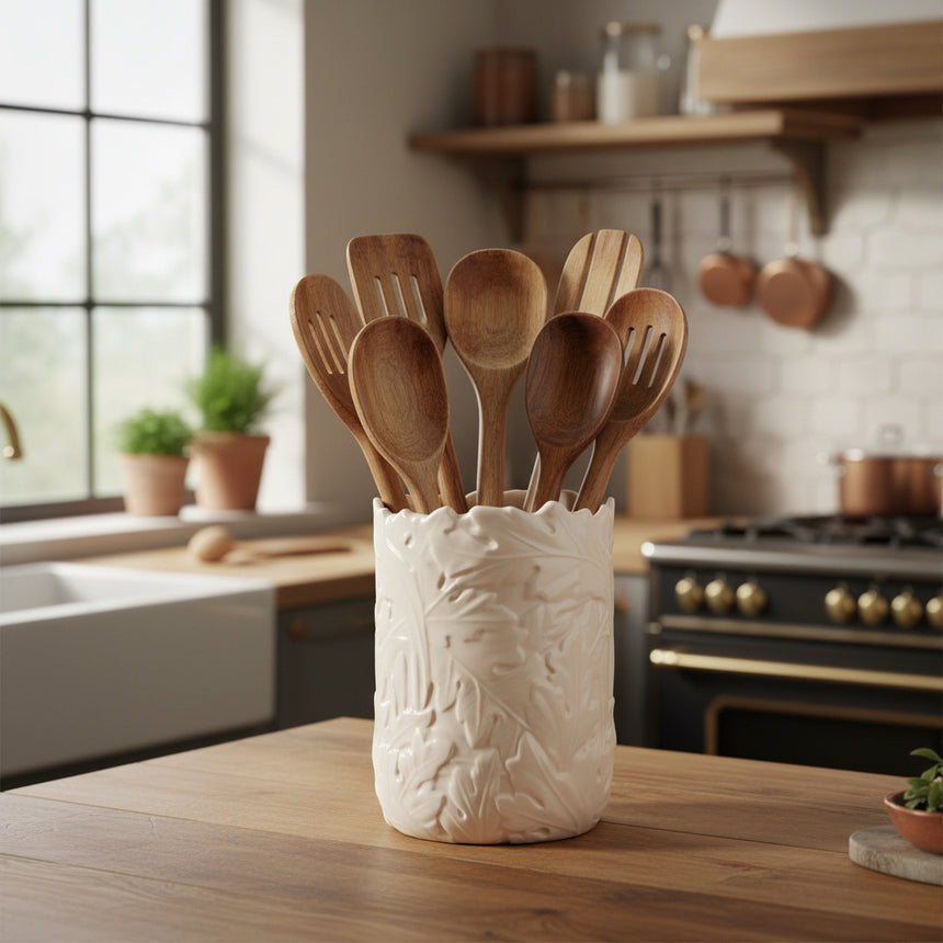 An off-white ceramic utensils holder with a textured, embossed leaf pattern and a rustic, unevenly broken rim, shown on a plain white background.