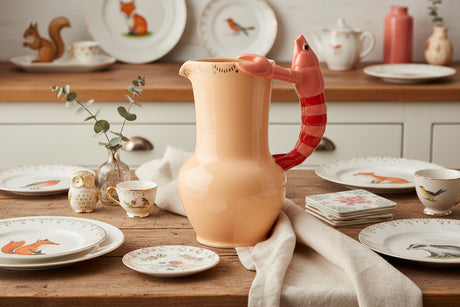 peach pitcher with a shrimp handle on a white background