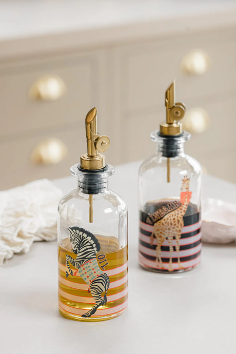 Two glass bottles with animal-themed designs and gold nozzles on a light background.