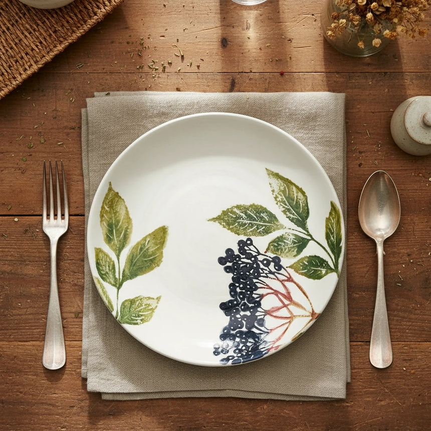 Round ceramic plate with leaf and berry design on a white background